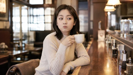 喫茶店のカウンターでコーヒーカップを持ち、ひとりの時間を過ごす女性